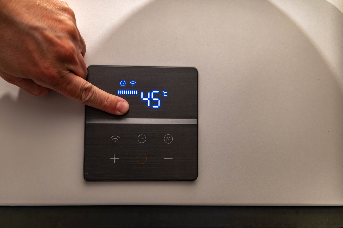 Person tippt auf ein schwarzes Tablet, um die Temperatur zu regulieren